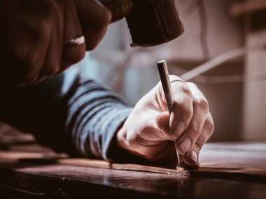 Deri usta çekiç kullanarak doğal deri ile çalışma kapatın. Yerel atölye çalışmalarında ustayı el çantası. El yapımı kavramı. Erkek Ayakkabıcılık Tekstil ile ürün oluşturma