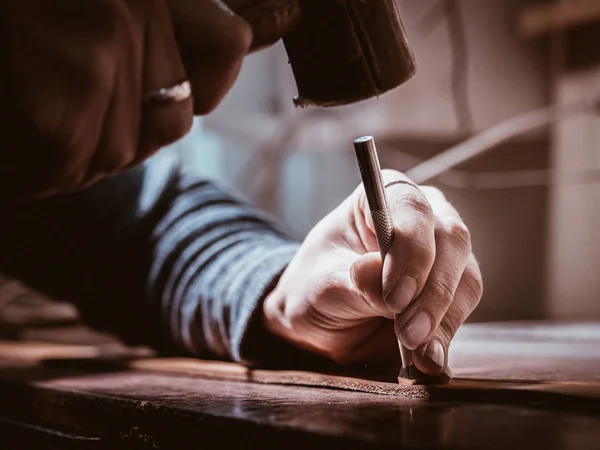 Primer plano de artesano de cuero trabajando con cuero natural usando martillo. Maestro de bolsos en el trabajo en taller local. Concepto hecho a mano. Zapatero masculino creando producto con textil —  Fotos de Stock