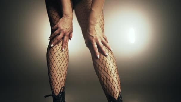 Jovem dançarina ajusta com as mãos sua meia-calça malha nas pernas nos saltos. Mulher acariciando seu corpo sexy. Senhora em foco de fumaça no palco. Movimento lento . — Vídeo de Stock