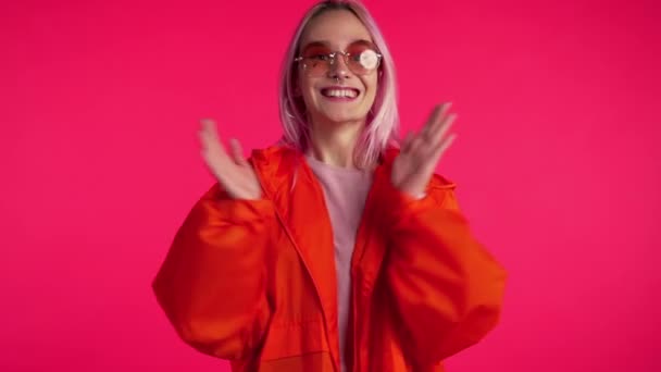 Porträtt av flicka med färgat rosa hår, klappar hon händerna med glädje. Förvånad glad kvinna. Blandad ras kvinna chockad modell på röd bakgrund. — Stockvideo