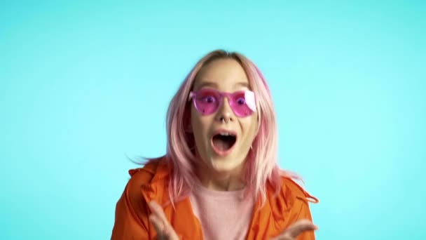 Förvånad glad lycklig kvinna skrikande wow. Porträtt av en ung flicka med extatiska ansiktsuttryck. Hipster chockad på blå bakgrund. — Stockvideo