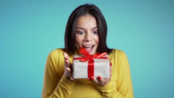 Donna eccitata ricevuto confezione regalo con fiocco. È felice e lusingata dall'attenzione. Ragazza su sfondo blu. Filmati dello studio . — Video Stock