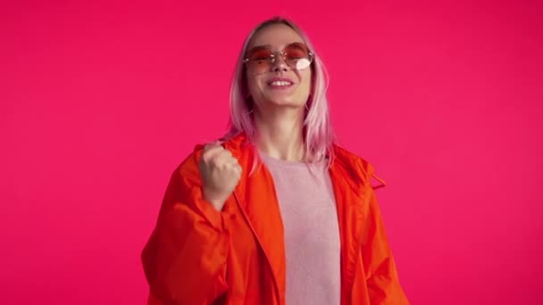 Mädchen mit rosa Haaren und außergewöhnliche Erscheinung zeigt ja Geste des Sieges, sie erreichte Ergebnis, Ziele. überrascht aufgeregt glücklich Hipster auf rotem Hintergrund — Stockvideo