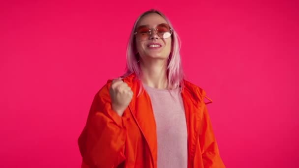 Fille aux cheveux roses et à l'apparence extraordinaire montre oui geste de victoire, elle a atteint le résultat, les objectifs. Surpris heureux hipster excité sur fond rouge — Video