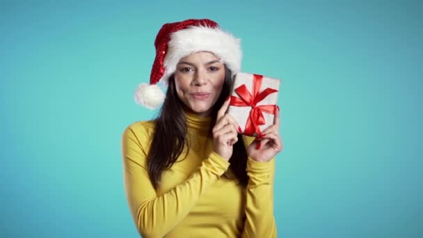 Mooie vrouw met kerstmuts met kistje op blauwe achtergrond. Kerstmis, Nieuwjaar vakantie concept. — Stockvideo