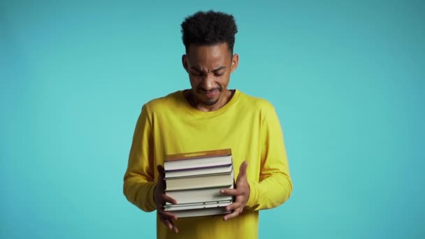 Estudiante africano está insatisfecho con la cantidad de deberes y libros. El hombre lanza libros, está molesto, desanimado frustrado por los estudios . — Vídeos de Stock