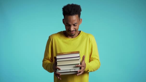 Estudiante africano está insatisfecho con la cantidad de deberes y libros. El hombre lanza libros, está molesto, desanimado frustrado por los estudios . — Vídeo de stock