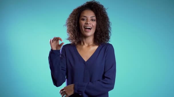 Mujer joven haciendo signo OK sobre fondo azul. Ganador. Éxito. Positivo joven africano chica sonrisas para cámara — Vídeos de Stock