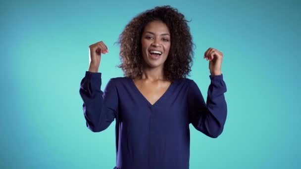 Businesswoman showing gesture of approval. Winner. Success. Positive young african girl on light blue background smiles for camera and gives thumbs up. — Stock Video