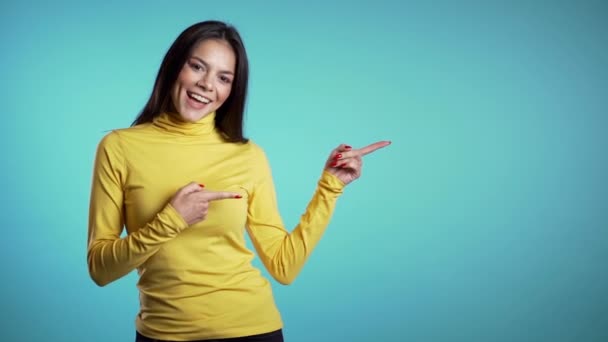 Mulher sorridente feliz no desgaste amarelo apresentando e mostrando algo isolado no fundo branco. Retrato de menina, ela apontando com os braços à esquerda com espaço de cópia . — Vídeo de Stock