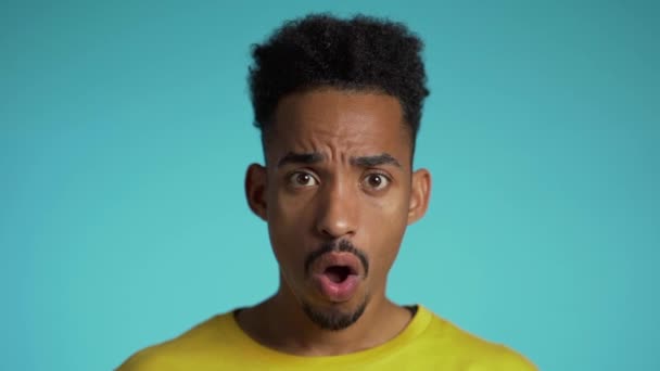 Homem de raça mista espantado chocado, dizendo WOW. Bonito afro americano cara com cabelo afro surpreso a câmera sobre fundo azul . — Vídeo de Stock