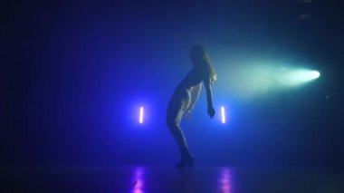 Harika bir kadın neon ışıkta dans ediyor. Profesyonel dansçı, müzik ritmine göre hareket ediyor. Yavaş çekim.