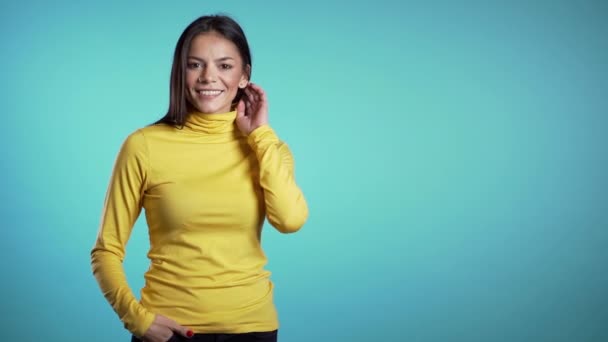 コピースペース青い壁の背景にカメラに笑みを浮かべて黄色の服の美しい陽気な混合レースの女性。かわいいですヒスパニック系の女の子の肖像. — ストック動画