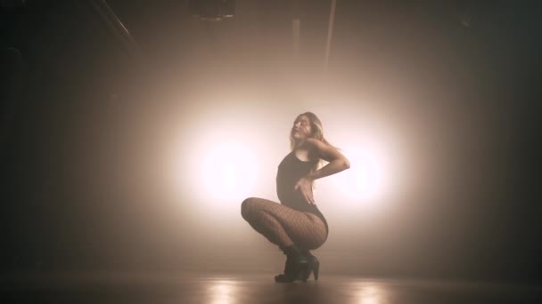 Hermosa mujer con el pelo largo en ropa sexy está bailando en habitación oscura. Danza moderna, estilo de vida, chica talentosa. Movimiento lento — Vídeo de stock