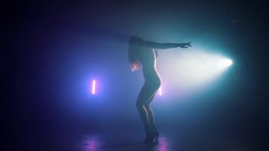 Harika bir kadın neon ışıkta dans ediyor. Profesyonel dansçı, müzik ritmine göre hareket ediyor. Yavaş çekim.