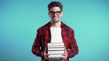 Stüdyoda mavi arka planda kırmızı ekose gömlekli Avrupalı öğrenci kütüphaneden bir yığın kitap tutuyor. Adam gülümsüyor, mezun olduğu için mutlu..
