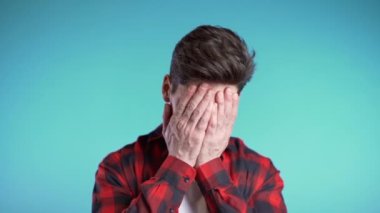Genç adam yüzünü ölümcül hayal kırıklığından ve başarısızlıktan dolayı elleriyle kapatıyor. Kırmızı ekose gömlekli depresif kayıp adam. Drama, duygu konsepti