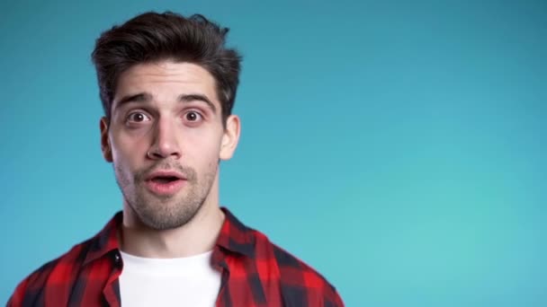 Copiar espacio. Retrato del joven hombre pensante en rojo teniendo idea momento señalando el dedo hacia arriba en el fondo del estudio azul. Sonriendo feliz estudiante chico mostrando eureka gesto . — Vídeos de Stock