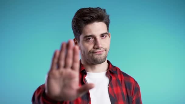 Não, nunca, homem morena bonito não gostando e rejeitando gesto por sinal de parada. Movimento lento. Retrato de jovem cara confiante de sucesso isolado em azul — Vídeo de Stock