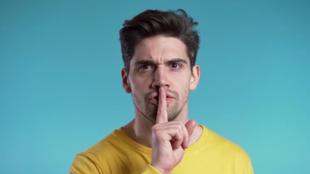 Hombre guapo europeo sosteniendo el dedo en sus labios sobre fondo azul. Gesto de shhh, secreto, silencio . — Vídeos de Stock