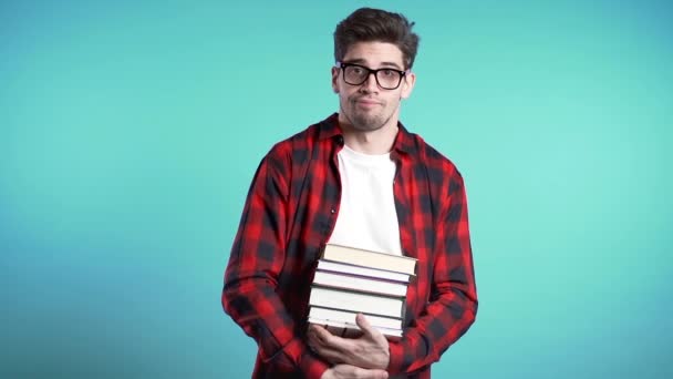 Evropský student na modrém pozadí je nespokojen s množstvím domácích úkolů a knih. Muž zmatený, je otrávený, znechucený studiem. — Stock video