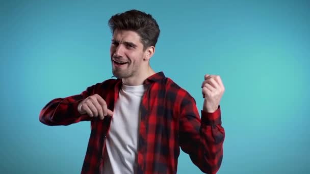 Happy european man dancing, showing yeah gesture of victory, he achieved result, goals. Surprised excited guy on blue background — Stock Video