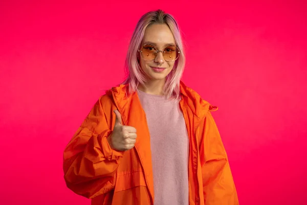 Jovem hipster fazendo polegares para cima sinal sobre fundo rosa. Vencedor. Sucesso. Menina positiva sorri para a câmera. Linguagem corporal . — Fotografia de Stock