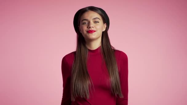 Ung hipster kvinna med röda läppar och hatt gör tummen upp skylt över rosa bakgrund. Vinnare. Framgång. En positiv tjej ler mot kameran. Kroppsspråk. Långsamma rörelser. — Stockvideo
