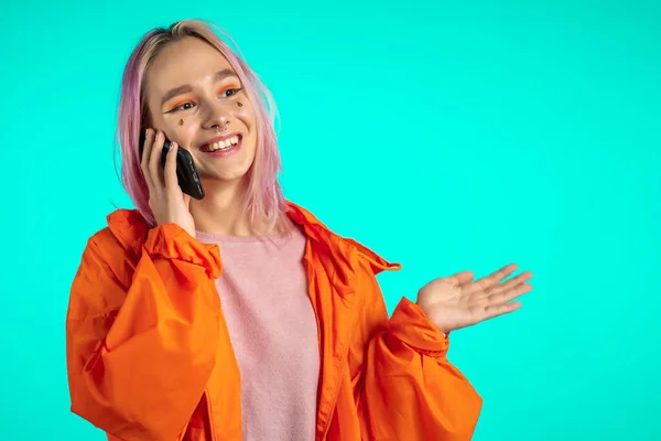 Όμορφη κοπέλα με ροζ μαλλιά μιλάει στο τηλέφωνο και γελάει μολυσμένα από αστεία συνομιλητών. Ασυνήθιστο μακιγιάζ, μοντέρνα ρούχα. Αντιγραφή χώρου. — Φωτογραφία Αρχείου