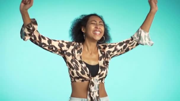 Porträt eines Mädchens mit lockigem Afro-Haar, sie tanzt komisch vor Freude. überrascht aufgeregt glückliche Frau gewinnt. Mischlingshündin schockiert Model auf blauem Hintergrund. — Stockvideo