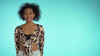 Uzayı kopyala Leopar desenli afro saçlı, mavi duvar arkasından kameraya gülümseyen güzel bir Afrikalı kadın. Şirin melez kızlar portresi.. 