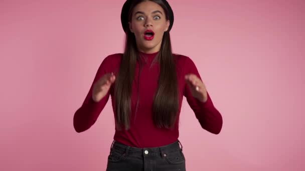 Portrait of cute girl shocked, saying WOW. Pretty woman with perfect make-up, stylish outfit pleasantly surprised to camera over pink background. — Stockvideo