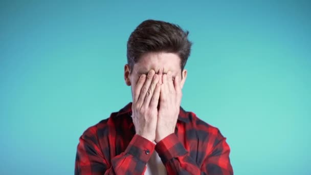 Young guy covers his face with hands from fatal disappointment, failure. Depressed lost man in red plaid shirt. Drama, emotions concept — Stock Video