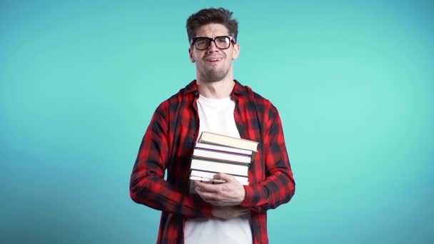 Estudiante europeo sobre fondo azul está insatisfecho con la cantidad de deberes y libros. El hombre lanza libros, está molesto, desanimado frustrado por los estudios . — Vídeos de Stock