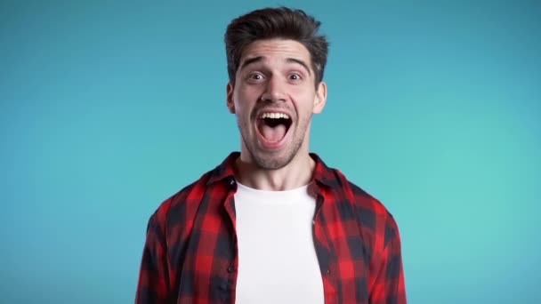 Amazed european man shocked, saying WOW. Handsome guy with stylish hairdo surprised to camera over blue background. — Stock Video