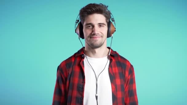 Knappe man met een koptelefoon die danst met geïsoleerde handen op een blauwe achtergrond. Feest, muziek, lifestyle, radio en disco concept. — Stockvideo