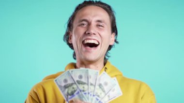 Mavi arka planda dolarları tutan adam. Para, zafer, başarı konsepti.