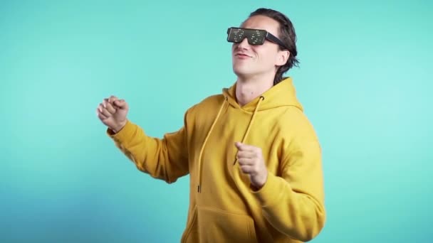 Mann in leuchtender Neon-Brille, der sich zum Musik-Rhythmus auf Studiohintergrund bewegt. tanzender positiver komischer Typ. Zeitlupe. — Stockvideo