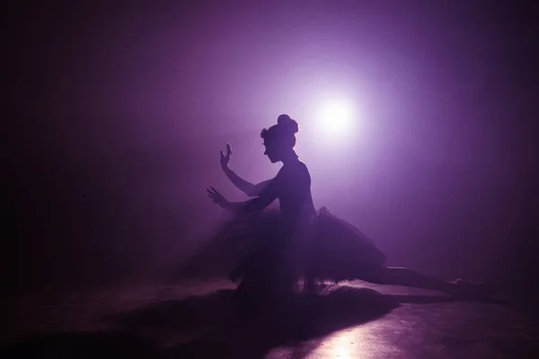 Silhueta de incrível menina dançando balé em tutu no palco na frente dos holofotes com luz de néon violeta colorida. Pintura volumétrica, cena de fumaça . — Fotografia de Stock