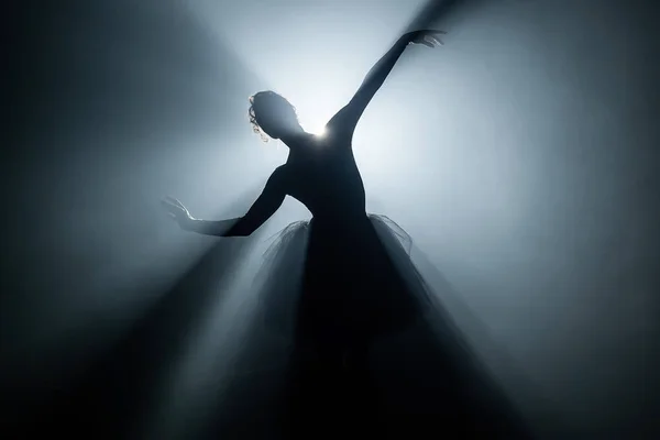 Spettacolo solista di ballerina in abito tutù sullo sfondo di luminosi riflettori al neon in teatro. Silhouette di donna in scarpe da punta ballando movimenti classici . — Foto Stock