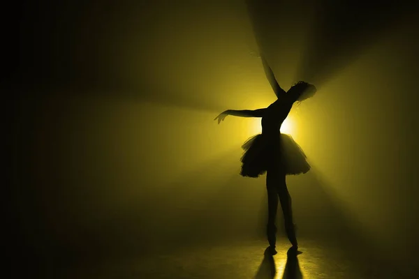 Αντιγραφή χώρου. Σιλουέτα της δραματικής κορίτσι χορό μπαλέτο σε τούτου στη σκηνή μπροστά από τα φώτα της δημοσιότητας με χρωματιστό κίτρινο νέον φως. Ογκομετρική ζωγραφική, σκηνή καπνού. — Φωτογραφία Αρχείου