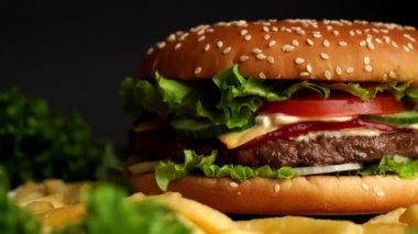 Et pirzolası, soğan, sebze, erimiş peynir, marul ve mayonez soslu büyük iştah açıcı burger. İzole edilmiş hamburger koyu duman arka planında döner, yakın plan görüntüsü