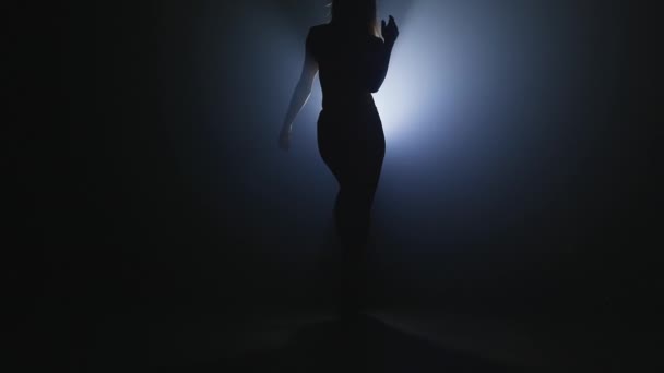 Mujer sexy delgada bailando en el escenario oscuro humo delante del proyector de luz. Concepto de artes, flexibilidad, chica talentosa . — Vídeo de stock