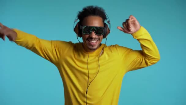 Hombre afroamericano con auriculares bailando con las manos aisladas sobre fondo azul. Fiesta, música, estilo de vida, radio y disco concepto . — Vídeos de Stock