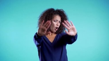 Kızgın sinirli kadın dur demek için ellerini kaldırıyor. Şüpheci ve şüpheci bakışlar, birine kızmak. Afro kız yüz ifadeleri, duygular ve duygular. Vücut dili.