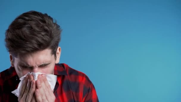 Young man sneezes into tissue. Isolated guy is sick, has a cold or allergic reaction. Health, medicine, illness, treatment concept — Stock Video