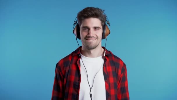 Hombre guapo con auriculares bailando con la cabeza aislada sobre fondo azul. Fiesta, música, estilo de vida, radio y disco concepto . — Vídeos de Stock