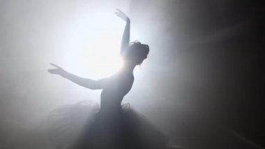 Tutu elbiseli balerin performansı, tiyatrodaki ışıklı neon spot ışıklarına karşı. Sivri uçlu ayakkabılı, klasik dans eden kadın silueti. 4k.