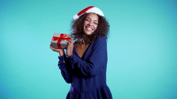 Mujer africana hermosa alegre con maquillaje perfecto celebración caja de regalo de plata con lazo. Chica de moda sonriendo, ella está feliz de estar presente. 4k — Vídeo de stock