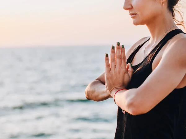 Mulher agradável faz saudação ao sol ao nascer do sol na costa do mar. Mãos no namaste. Yoga, meditação, gratidão, conceito de estilo de vida saudável . — Fotografia de Stock